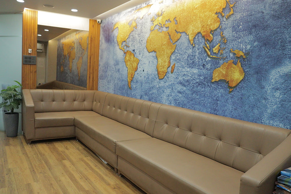 waiting room area with a 8 seat sofa and worldmap on the wall at hairfree and hairgrow clinic
