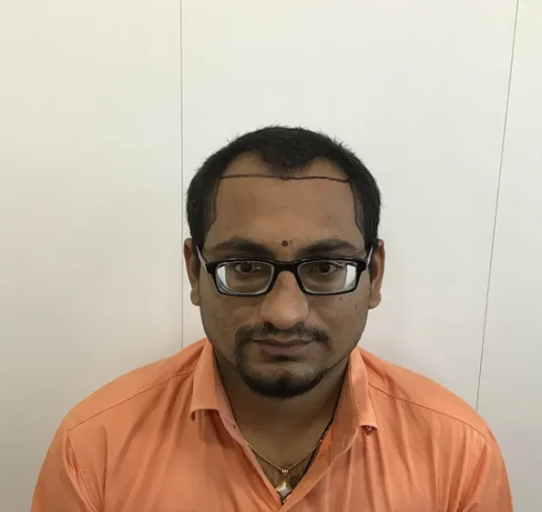 Man wearing orange shirt, seated.